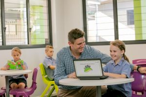 Student working with a teacher using a laptop in a classroom supporting digital learning and guided instruction