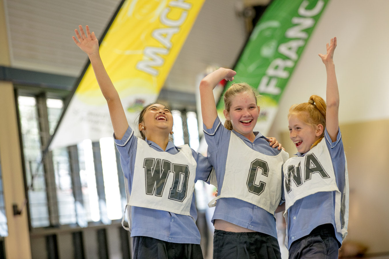 Students celebrating together in a netball game with raised arms highlighting teamwork achievement and active participation in school sport