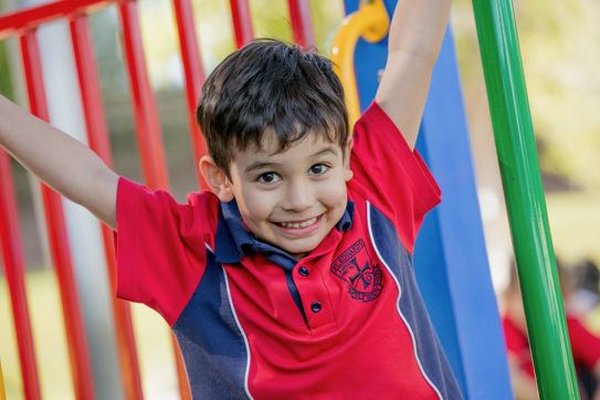 Student climbing on playground equipment with arms raised promoting confidence active play and physical development
