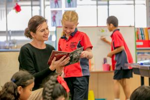 Female Teacher reading with a student in a classroom promoting literacy development and supportive learning relationships