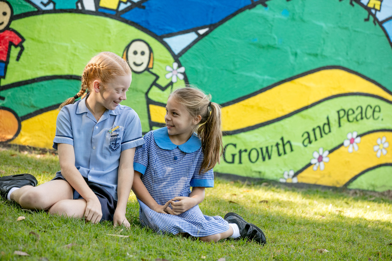 Students sitting together outdoors in front of a colourful mural highlighting friendship belonging and a strong sense of community within the school environment
