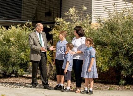 School principal speaking with a parent and students outdoors highlighting strong relationships family engagement and a welcoming school community