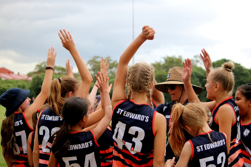 Students high fiving as a team during a sports game highlighting teamwork encouragement and active participation