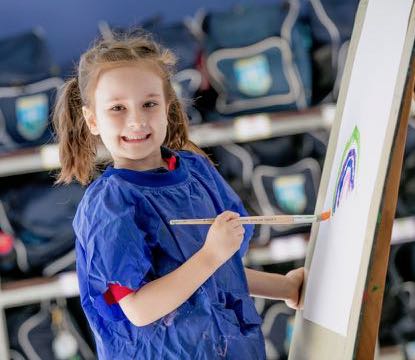 Student painting on an easel in a classroom art space promoting creativity self expression and engagement in visual arts learning